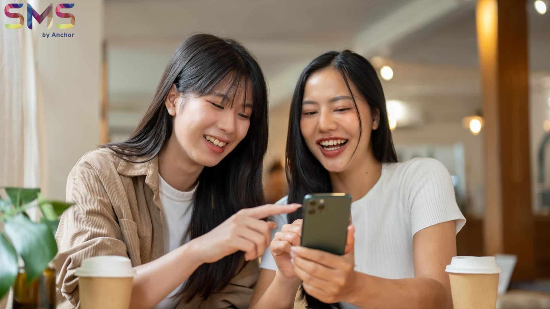 Girls receiving sms broadcast of flash sales happily in mobile phone